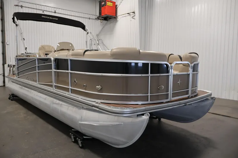 Slide: The Image of 2016 Berkshire 23E STS pontoon boat in indoor storage, featuring beige seating and sleek design. - 3