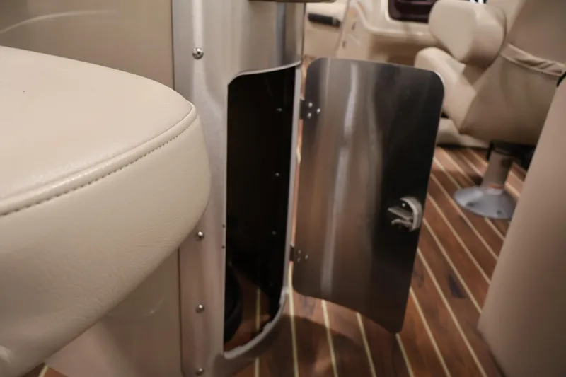 Slide: The Image of Open storage compartment on 2016 Berkshire 23E STS boat with beige seating and wood flooring. - 34