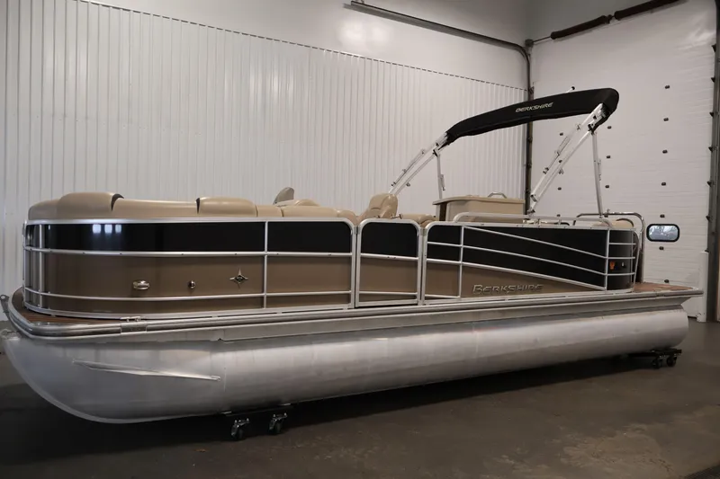 Slide: The Image of 2016 Berkshire 23E STS pontoon boat in indoor storage, featuring beige and black design. - 8