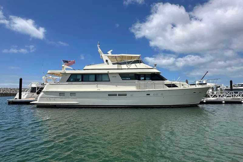 The Image of 1992 Hatteras 65 Motor Yacht docked in a marina under a blue sky. - 0