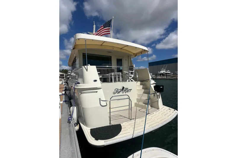 Slide: The Image of 1992 Hatteras 65 Motor Yacht docked, featuring American flag and spacious deck. - 1