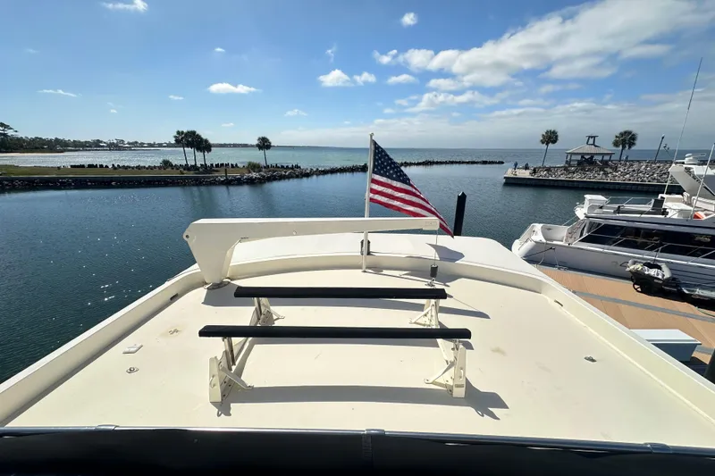 Slide: The Image of 1992 Hatteras 65 Motor Yacht deck with American flag, overlooking serene marina and palm trees. - 35