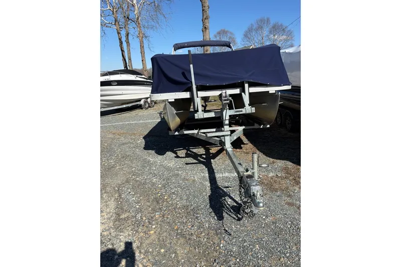 Slide: The Image of 2006 Triton 220 F Gold boat on trailer, covered, parked outdoors. - 2