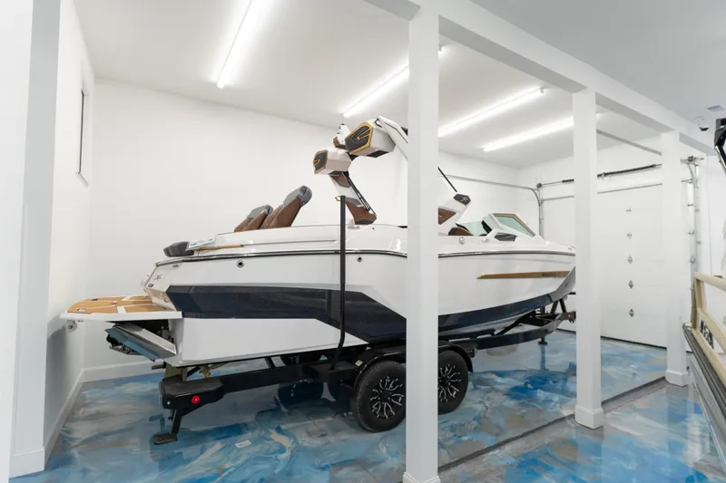 The Image of 2026 MasterCraft X24 boat in a modern garage with blue epoxy floor. - 0