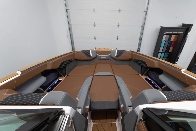 Slide: The Image of 2026 MasterCraft X24 boat interior with brown and gray seating in a showroom. - 2