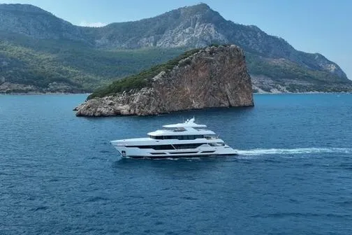 Slide: The Image of Luxurious 2025 Hargrave E Series yacht cruising near a rocky island backdrop. - 38