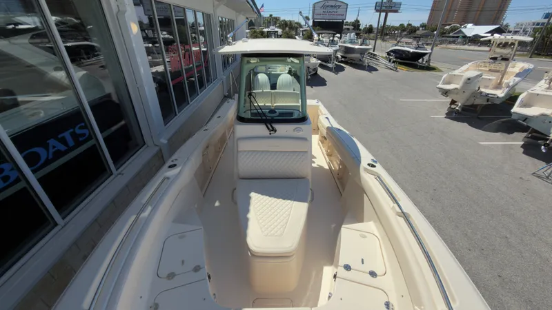Slide: The Image of The image shows a 2027 Grady-White Canyon 266 boat. It is parked next to a building with large windows. The boat features cream-colored upholstery and a modern design. - 16