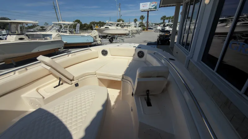 Slide: The Image of The image shows the cockpit of a Grady-White Canyon 266 boat. It features beige upholstery and is parked in a showroom. - 12