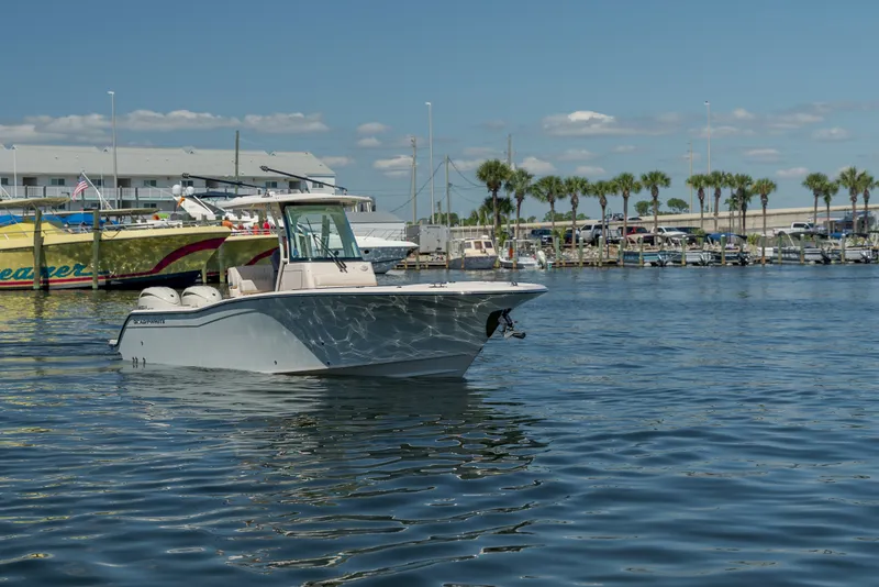 Slide: The Image of A 2027 Grady-White Canyon 266 boat floats in a harbor with palm trees in the background. - 5