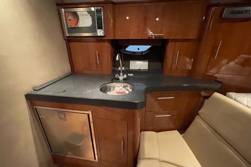 Slide: The Image of 2013 Regal 35 Sport Coupe interior kitchen with microwave, sink, and wooden cabinetry. - 46