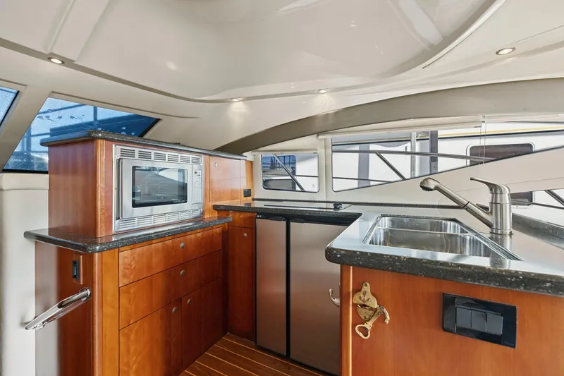 Slide: The Image of 2008 Cruisers Yachts 447 Sport Sedan kitchen with microwave, sink, and wooden cabinetry. - 10
