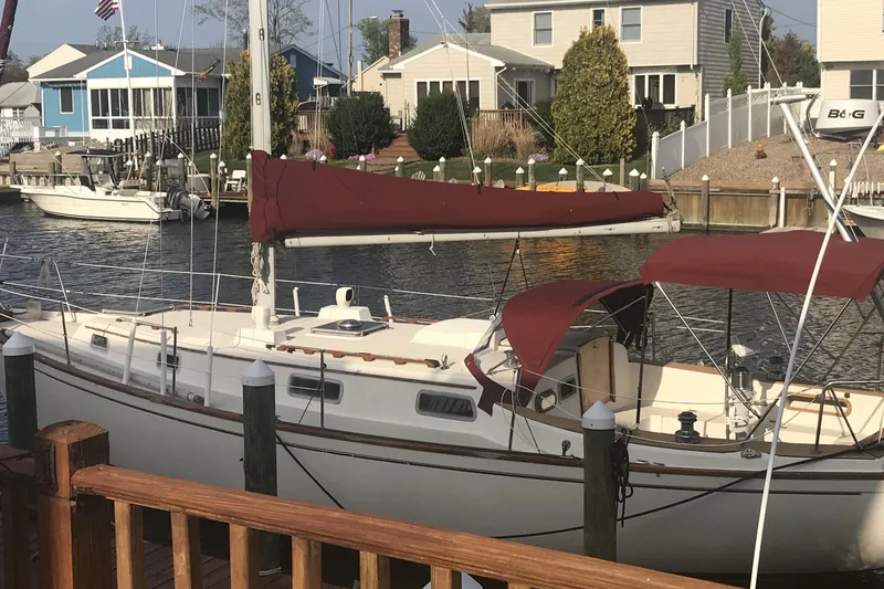 The Image of 1980 Pearson 365 Sloop docked in a marina, featuring maroon sails and canopy. - 0