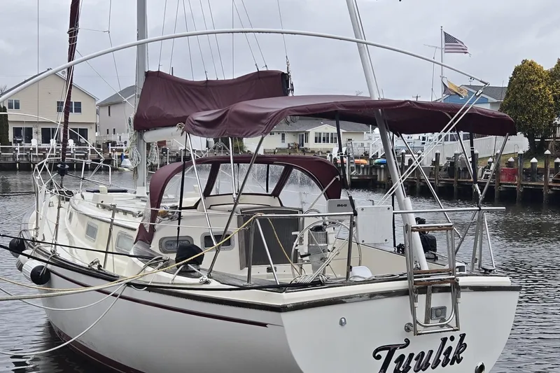 Slide: The Image of 1980 Pearson 365 Sloop docked, displaying an American flag under cloudy skies. - 5