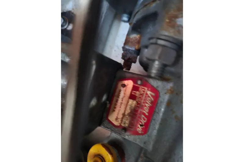 Slide: The Image of Close-up of a 1980 Pearson 365 Sloop engine component with visible label and bolts. - 63