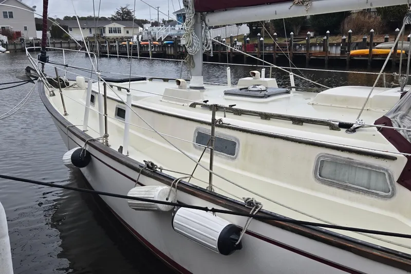 Slide: The Image of 1980 Pearson 365 Sloop docked in a marina, featuring classic design and maroon sail cover. - 9