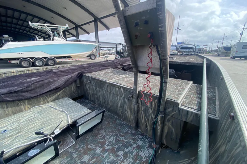 Slide: The Image of 2009 Gator Trax MUD BUDDY 17 X 50 boat with camo interior, parked under shelter. - 16