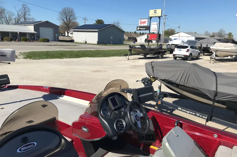 Slide: The Image of 2008 Triton 18 Explorer boat in a dealership lot with covered boats and cars. - 10