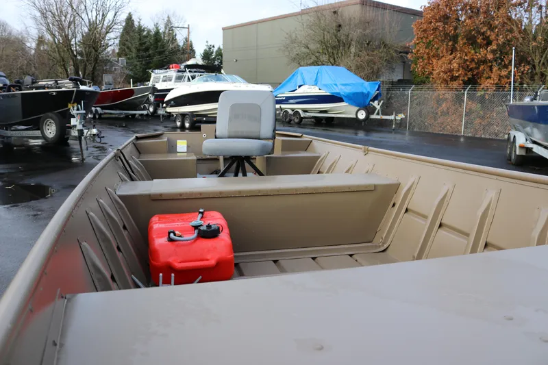 Slide: The Image of 2025 Smoker Craft 1648 Jon boat with seating and fuel tank, parked outdoors. - 7