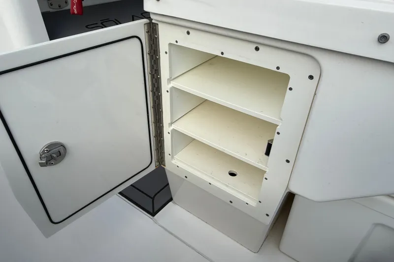 Slide: The Image of Open storage compartment on a 2023 Solace 30 HCS boat, featuring shelves and a secure latch. - 31