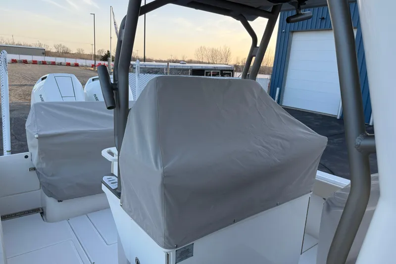 Slide: The Image of 2023 Solace 30 HCS boat with covered console and engines, docked near a blue building. - 51