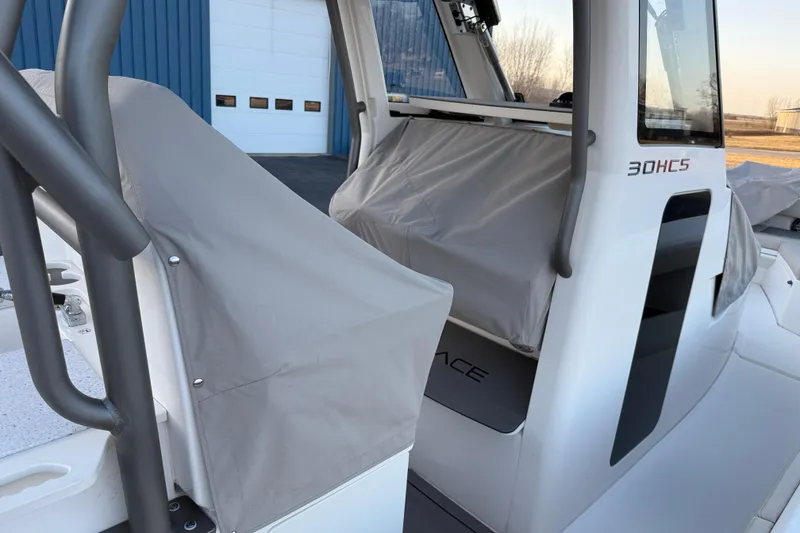 Slide: The Image of 2023 Solace 30 HCS boat with protective covers, docked near a blue building. - 53