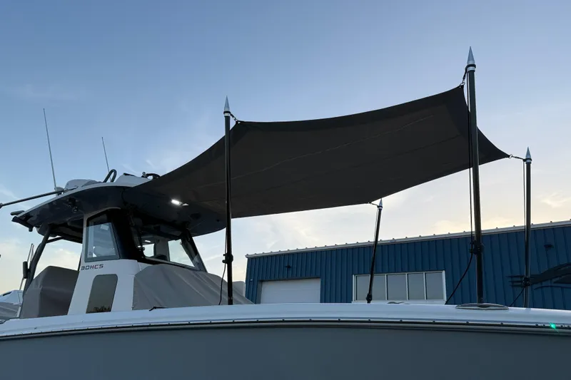 Slide: The Image of 2023 Solace 30 HCS boat with canopy, docked near a blue building at sunset. - 55