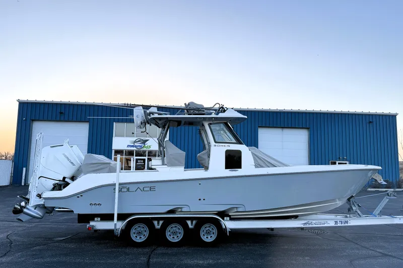Slide: The Image of 2023 Solace 30 HCS boat on trailer, parked outside blue industrial building. - 8