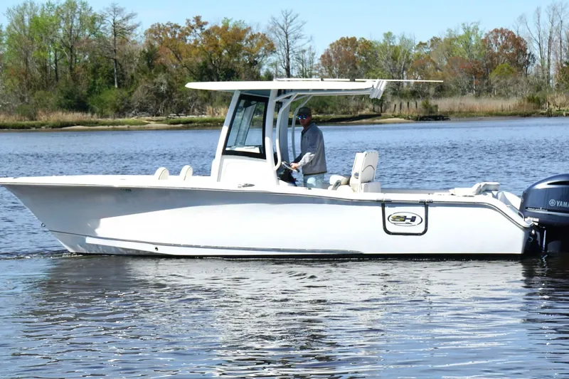 The Image of 2021 Sea Hunt Ultra 255 SE boat cruising on a calm lake with trees in the background. - 1