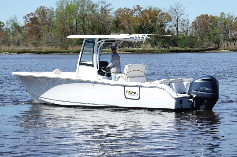 Slide: The Image of 2021 Sea Hunt Ultra 255 SE boat on calm water with trees in the background. - 6