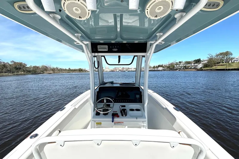 Slide: The Image of 2021 Sea Hunt Ultra 255 SE boat interior with steering wheel on calm water. - 8
