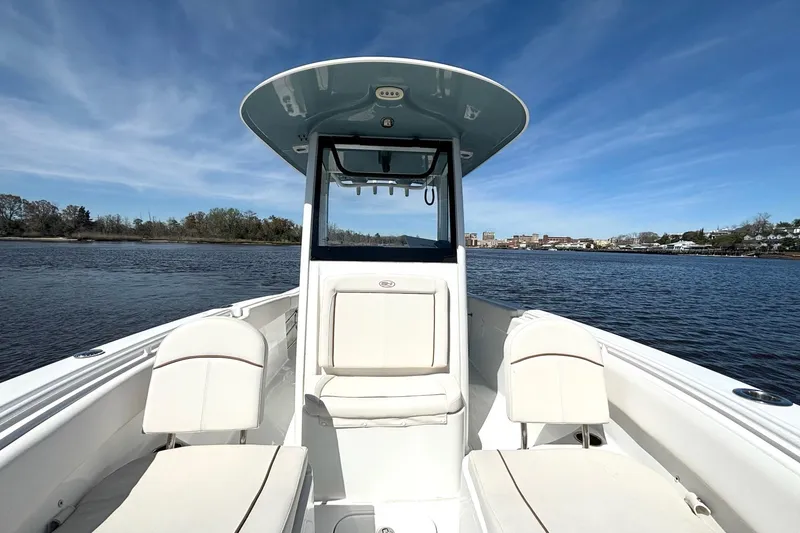 Slide: The Image of 2021 Sea Hunt Ultra 255 SE boat on calm water under clear blue sky. - 9