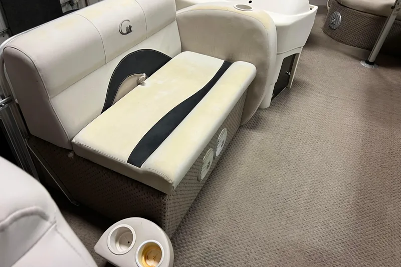Slide: The Image of 2014 Avalon Grand Island 2485 QF boat interior with beige seating and cup holders. - 12