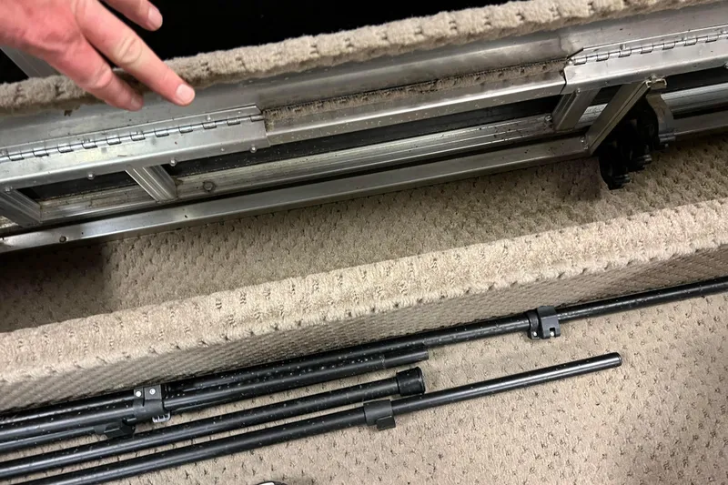 Slide: The Image of 2014 Avalon Grand Island 2485 QF boat interior with storage compartment and metal rods. - 58