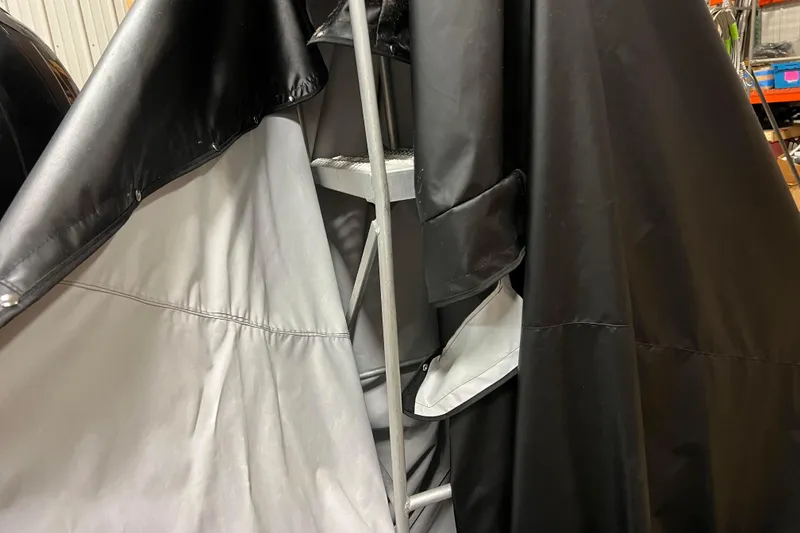 Slide: The Image of 2014 Avalon Grand Island 2485 QF boat covered with black and gray tarps in storage. - 81