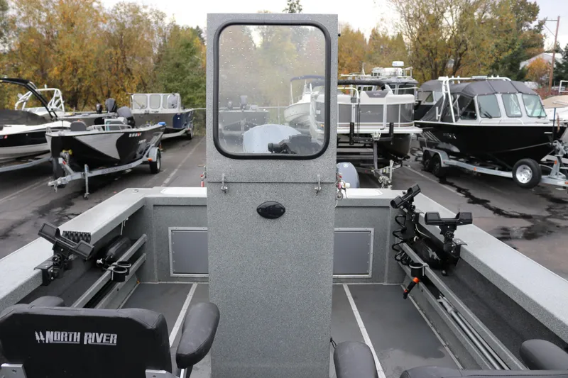 Slide: The Image of 2022 North River Osprey boat interior with fishing rod holders, parked among other boats. - 15