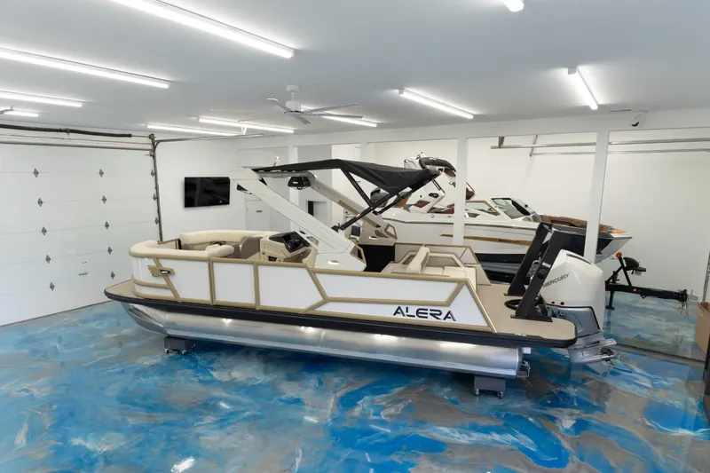 The Image of 2026 Alera M23Q boat in a modern garage with blue epoxy floor. - 0