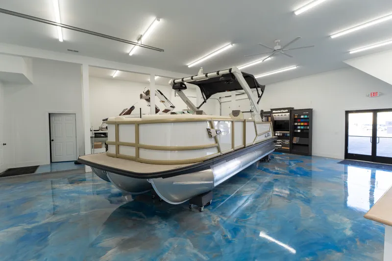 Slide: The Image of 2026 Alera M23Q pontoon boat displayed in a modern showroom with blue flooring. - 2