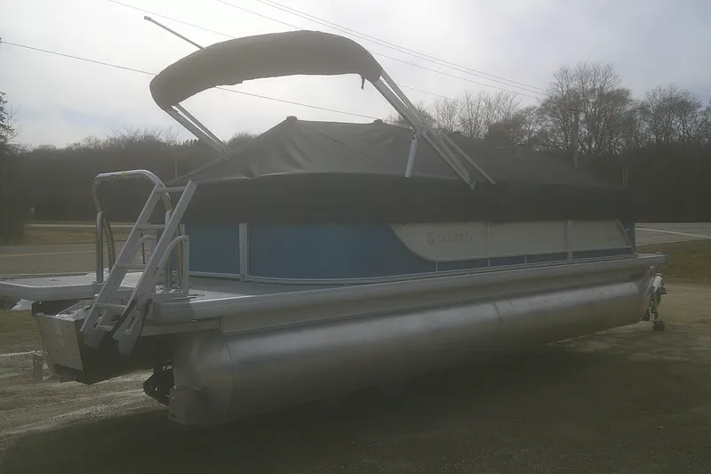 Slide: The Image of 2026 Godfrey EX 2286 SBX pontoon boat with canopy, parked on a roadside. - 15