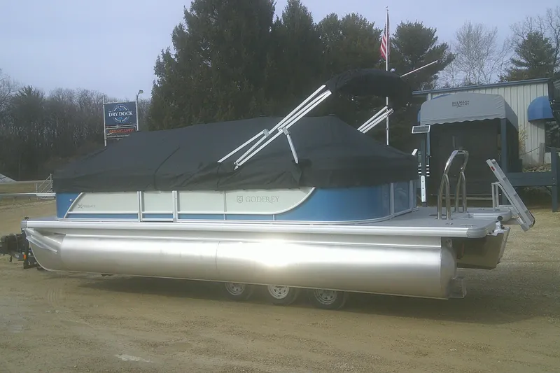 Slide: The Image of 2026 Godfrey EX 2286 SBX pontoon boat with cover, parked on a trailer. - 16
