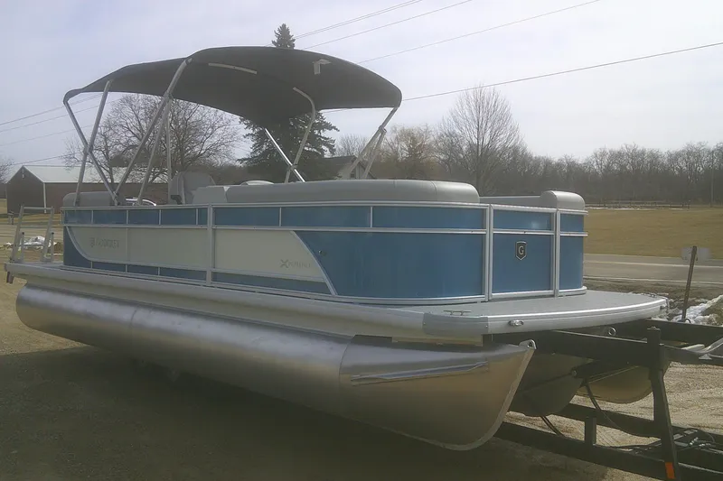 Slide: The Image of 2026 Godfrey EX 2286 SBX pontoon boat with canopy, parked on a trailer. - 3