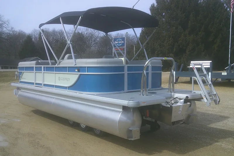 Slide: The Image of 2026 Godfrey EX 2286 SBX pontoon boat with blue and silver design, parked outdoors. - 4
