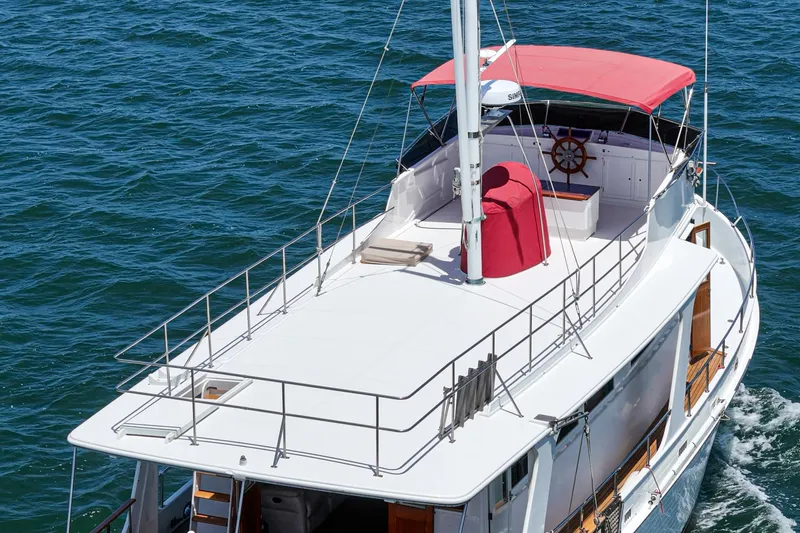 Slide: The Image of 1971 Grand Banks yacht with red canopy cruising on blue ocean waters. - 15