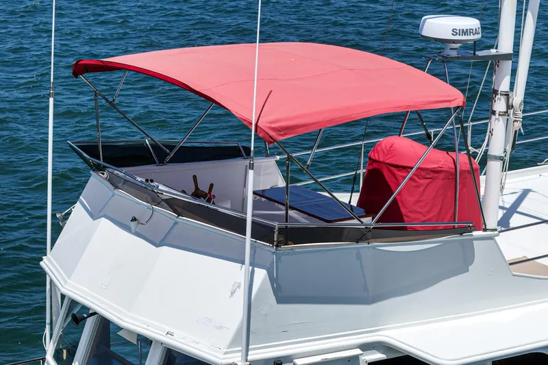 Slide: The Image of 1971 Grand Banks boat with red canopy and seating, anchored on blue water. - 16