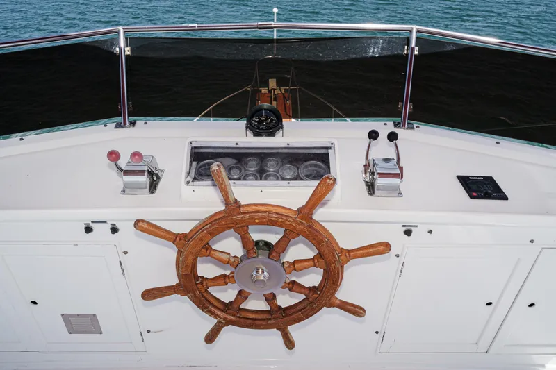 Slide: The Image of 1971 Grand Banks boat helm with wooden wheel and control panel on open water. - 18