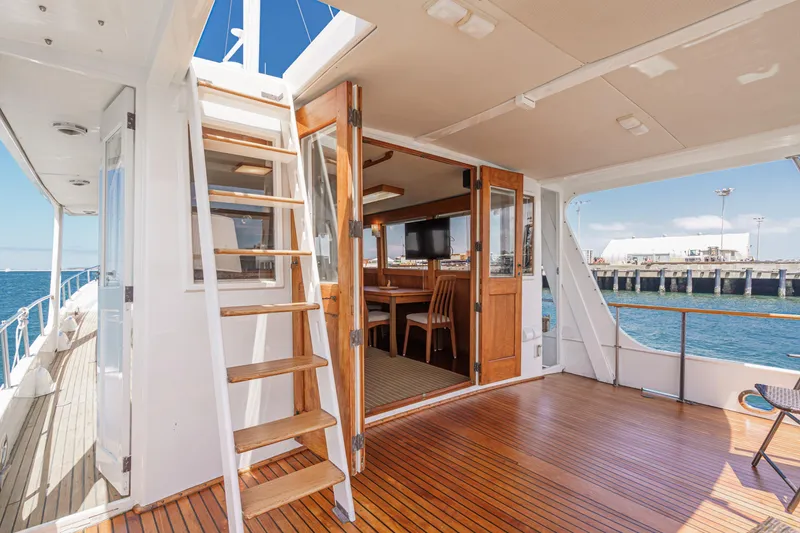 Slide: The Image of 1971 Grand Banks yacht deck with wooden flooring, stairs, and open cabin view. - 20