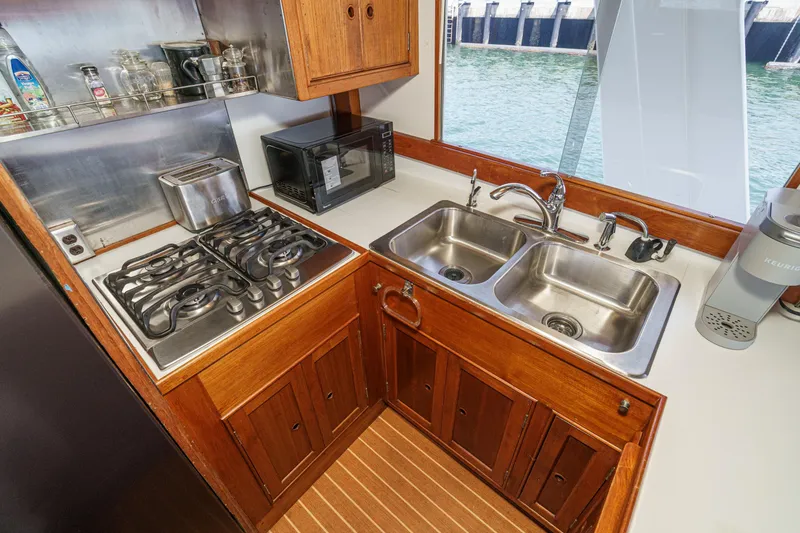 Slide: The Image of 1971 Grand Banks boat kitchen with stove, sink, and microwave by a window. - 28