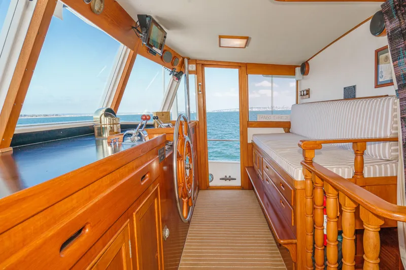 Slide: The Image of 1971 Grand Banks boat interior with wooden helm, striped seating, and ocean view. - 29