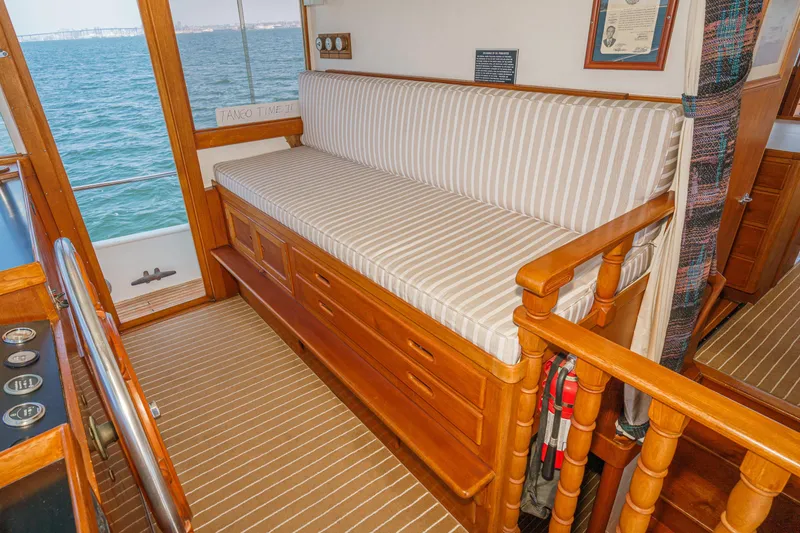 Slide: The Image of 1971 Grand Banks boat interior with striped seating, wooden accents, and ocean view. - 32