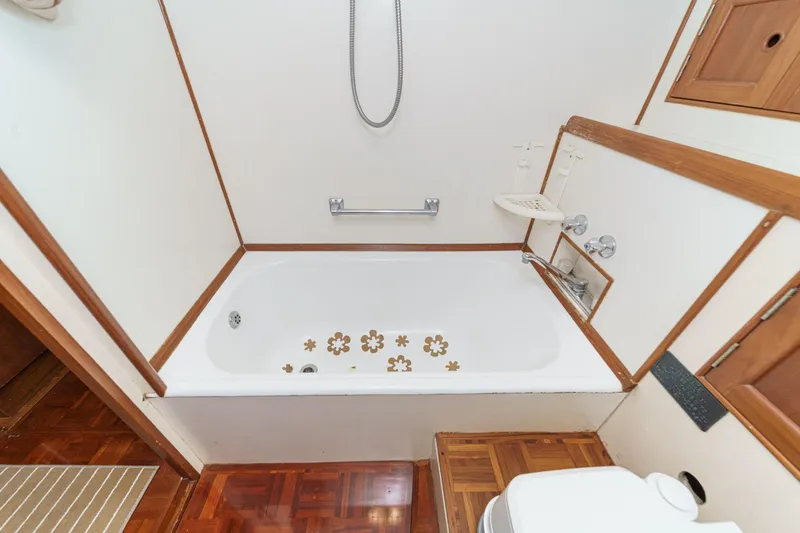 Slide: The Image of 1971 Grand Banks boat bathroom with bathtub, wooden accents, and floral decals. - 42