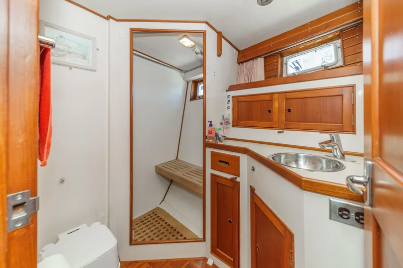 Slide: The Image of 1971 Grand Banks boat bathroom with wooden cabinets, sink, and shower area. - 45